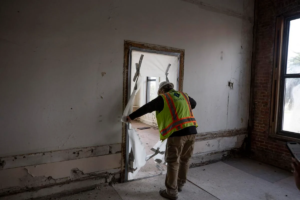 Greg Estabrook cuts open the plastic sheet to walk through the admirals room where the admiral of the Navy Base would work from Storehouse 8 in North Charleston on Friday, Jan. 27, 2023